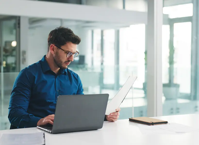 Businessman analyzing paperwork at computer