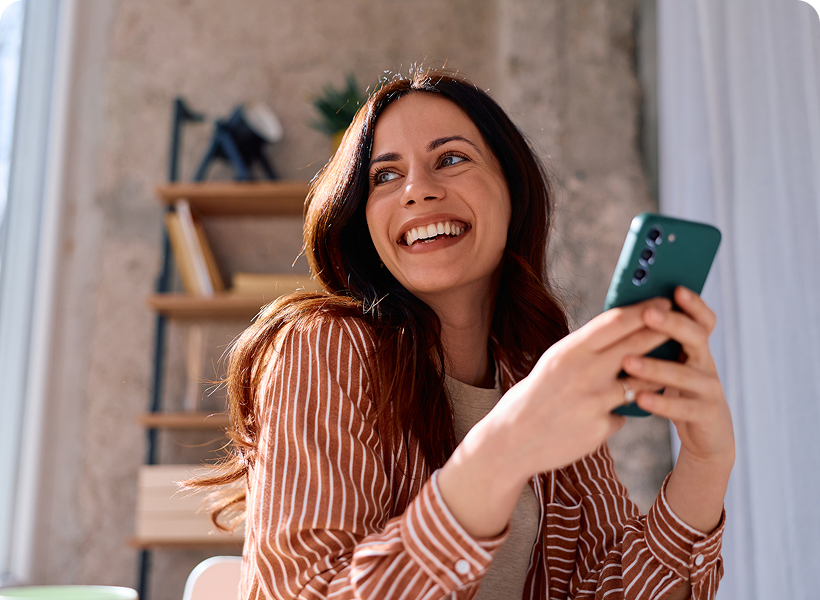 Happy woman with phone in cozy room